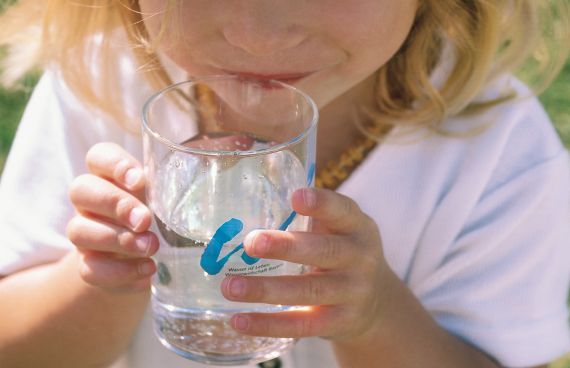 Mädchen trinkt aus Glas mit Wasser